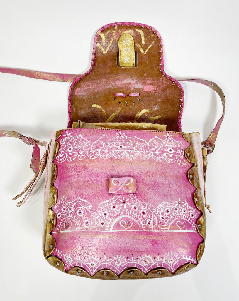 Émilie is a handpainted, up-cycled leather handbag by Mer Rose Atelier, pink is the  main color with ribbons, bows and lace designs.